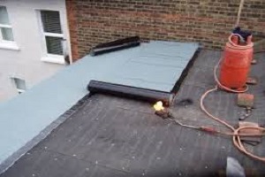 Applying top layers of green mineral felt to an extension flat roof with a heat gun
